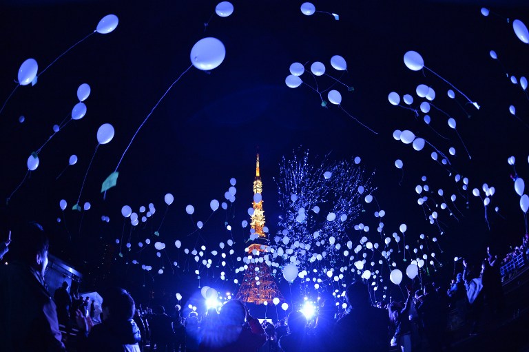 People release balloons to celebrate the New Year at the Prince Park Tower in Tokyo on January 1, 2016.  More than 1,000 balloons were released, carrying with them new year wishes.   / AFP / KAZUHIRO NOGI