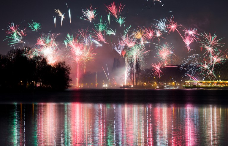 Exploding fireworks reflect in the water of the Maschsee lake in Hanover, central Germany, during New Year's celebrations on January 1, 2016. / AFP / dpa / Julian Stratenschulte / Germany OUT