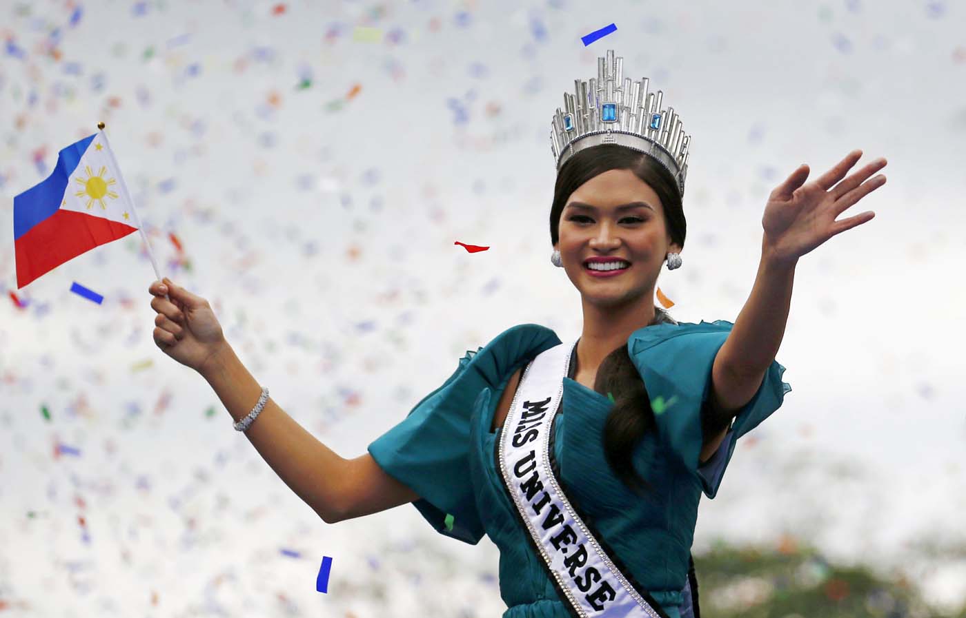 Miss Universe 2015 Pia Alonzo Wurtzbach holds a miniature Philippines flag as she waves to the crowd during a motorcade along Roxas Boulevard in Manila, January 25, 2016. Wurtzbach, the first Miss Universe from the Philippines in more than four decades, said on Sunday she will spend her reign bringing awareness to issues like HIV and draw support for countries vulnerable to disasters. REUTERS/Erik De Castro      TPX IMAGES OF THE DAY