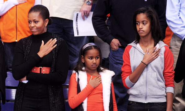 WASHINGTON - NOVEMBER 27: (AFP OUT) U.S. first lady Michelle Obama and daughters Malia and Sasha stand for the National Anthem during a college basketball game at Howard University November 27, 2010 in Washington, DC. President Barack Obama attended the game between Howard University and Oregon State, which is coached by his brother-in-law Craig Robinson. (Photo by Olivier Douliery-Pool/Getty Images)