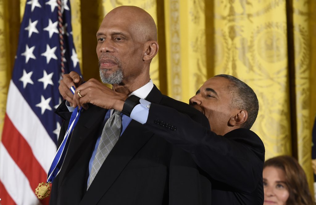 US President Barack Obama reaches up to NBA star Kareem Abdul-Jabbar as he presentshim with the Presidential Medal of Freedom, the nation's highest civilian honor, during a ceremony honoring 21 recipients, in the East Room of the White House in Washington, DC, November 22, 2016. / AFP PHOTO / SAUL LOEB