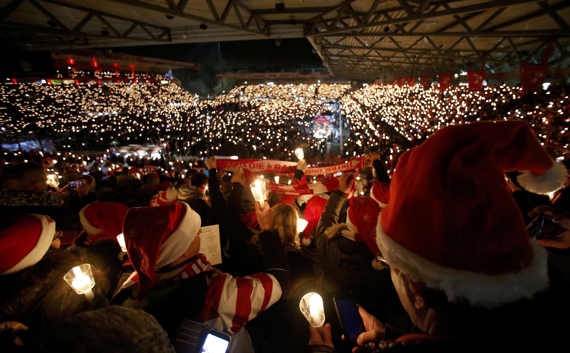 People attend the "Weihnachtssingen", a candle-lit carol concert with 28500 fans of the second-division club FC Union Berlin at the Alte Foersterei stadium in Berlin, Germany, December 23, 2016. REUTERS/Hannibal Hanschke