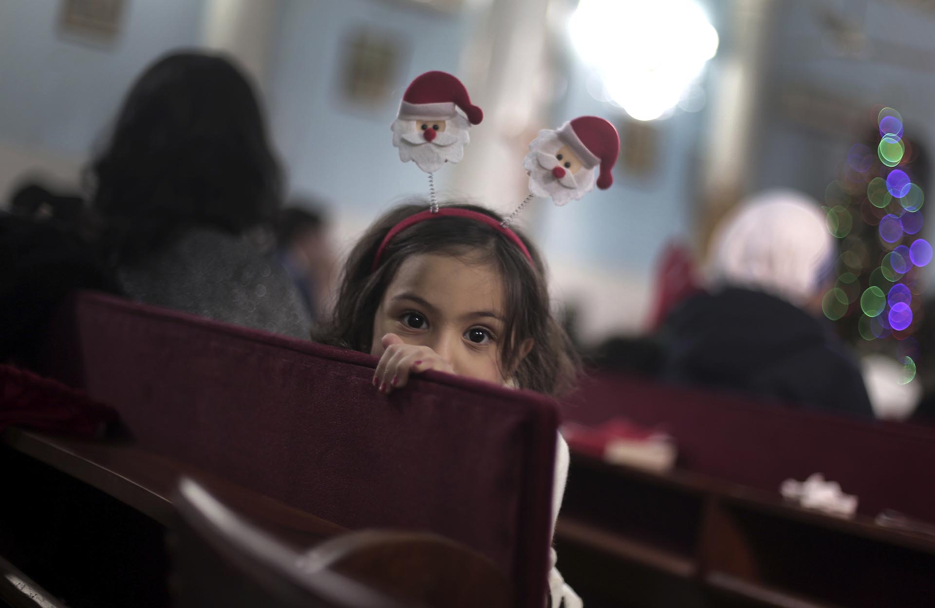 A Palestinian Christian girl attends with her family, the prayers on Christmas Eve at the Holy Family Catholic Church in Gaza City, Saturday, Dec. 24, 2016. (AP Photo/ Khalil Hamra)