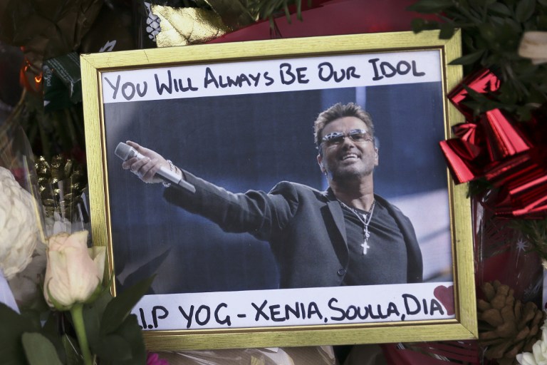 A photograph of British singer George Michael is seen among floral tributes and candles outside Michael's north London home on December 26, 2016, after news of the singer's death broke. Tributes poured in from the music world on December 26 after British pop superstar George Michael, who rose to fame with the duo Wham! and a string of smash hits including "Last Christmas", died aged 53. Michael died of apparent heart failure on Christmas Day at his home in Goring, a village on the River Thames in Oxfordshire, west of London, after an award-winning career spanning more than three decades. / AFP PHOTO / Daniel LEAL-OLIVAS