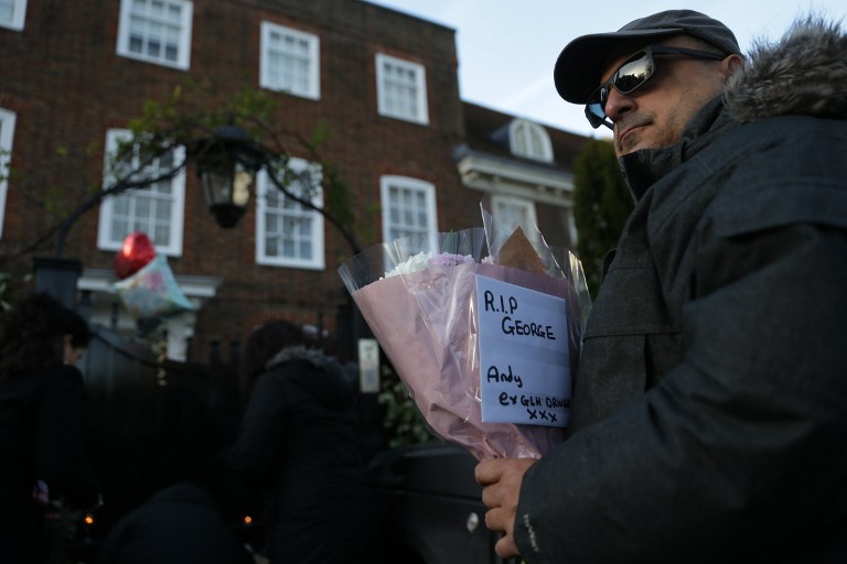 People arrive with bunches of flowers to lay in tribute outside the north London home of British singer George Michael on December 26, 2016, after news of the singer's death broke. Tributes poured in from the music world on December 26 after British pop superstar George Michael, who rose to fame with the duo Wham! and a string of smash hits including "Last Christmas", died aged 53. Michael died of apparent heart failure on Christmas Day at his home in Goring, a village on the River Thames in Oxfordshire, west of London, after an award-winning career spanning more than three decades. / AFP PHOTO / Daniel LEAL-OLIVAS